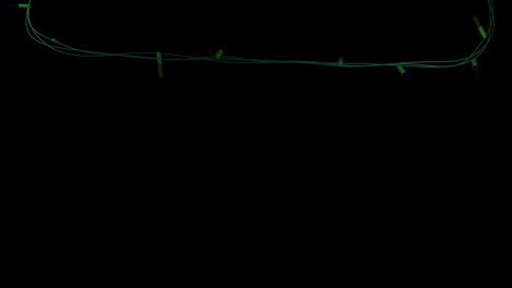 una cadena de luces de color de navidad que parpadean sobre un fondo negro, copia el espacio
