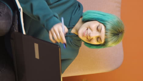 video vertical de una mujer joven trabajando en una computadora portátil con una expresión feliz.