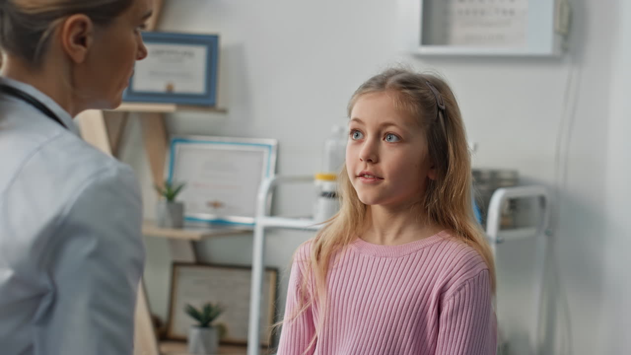 Pediatrician testing kid eyes reflexes during checkup. Closeup cute blond girl