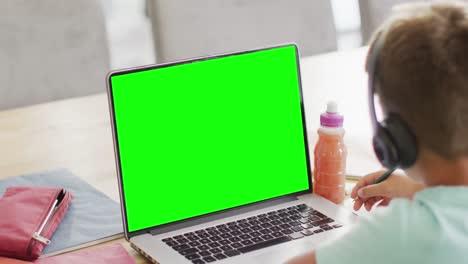 Composition-of-caucasian-schoolboy-on-laptop-online-learning-with-green-screen