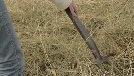 farmer turning hay stack with fork