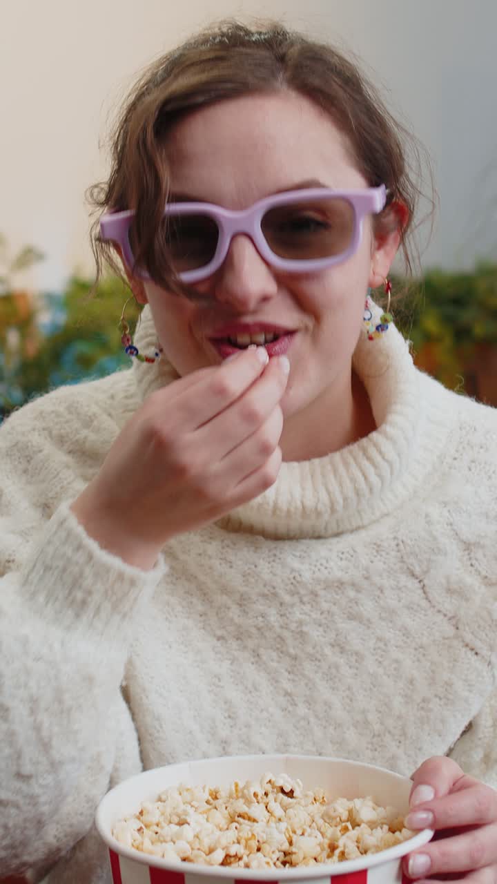 Mulher sentada no sofá comendo pipoca e vendo televisão interessante 3D filme jogo de esporte on-line em casa