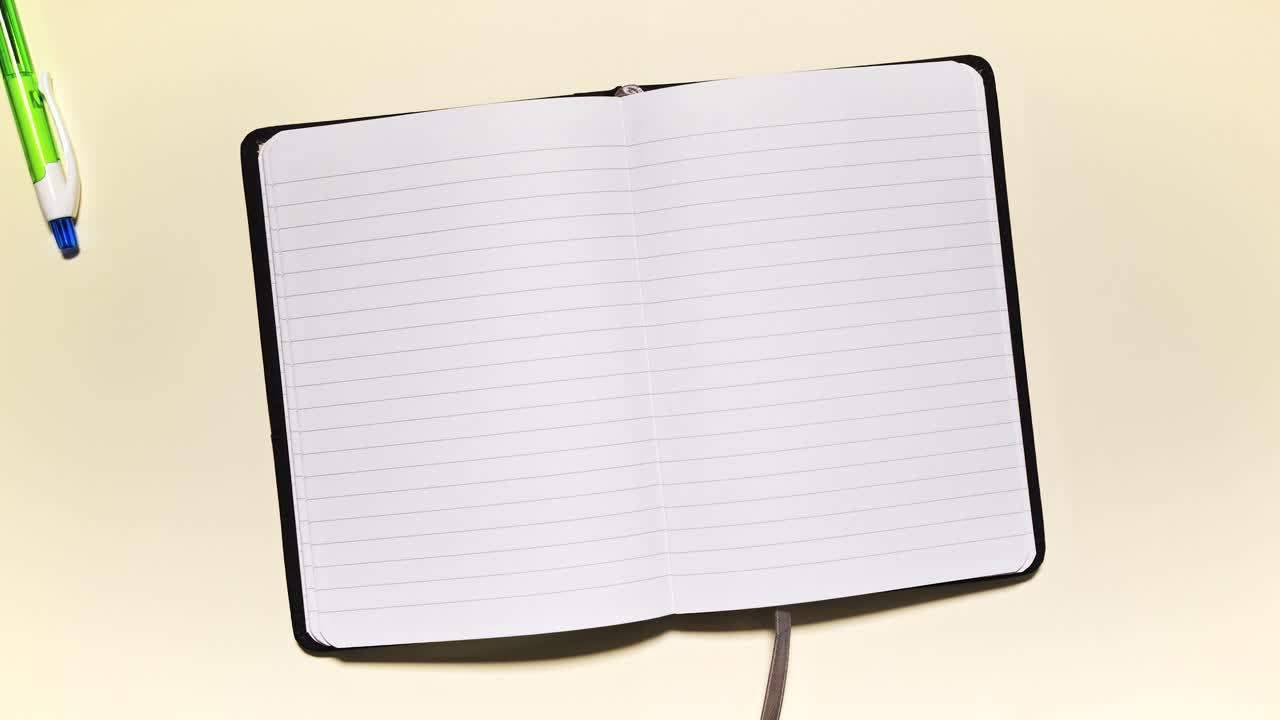 Stop motion of stationery framing an open lined notebook, leaving clean copy space on a light background