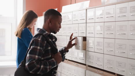 un estudiante buscando información en un catálogo de tarjetas de la biblioteca