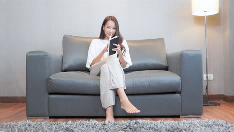 Hermosa-Mujer-En-Casa-Sentada-En-El-Sofá-Leyendo-Un-Libro