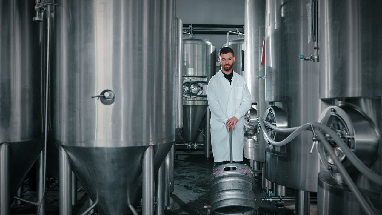 trabajador de una cervecería en una sala de tanques de acero inoxidable