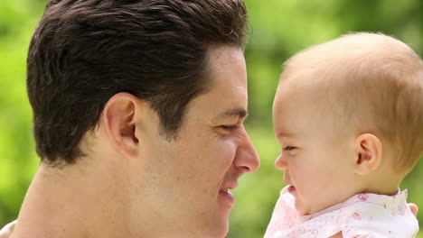 padre feliz sosteniendo a su niña en el parque