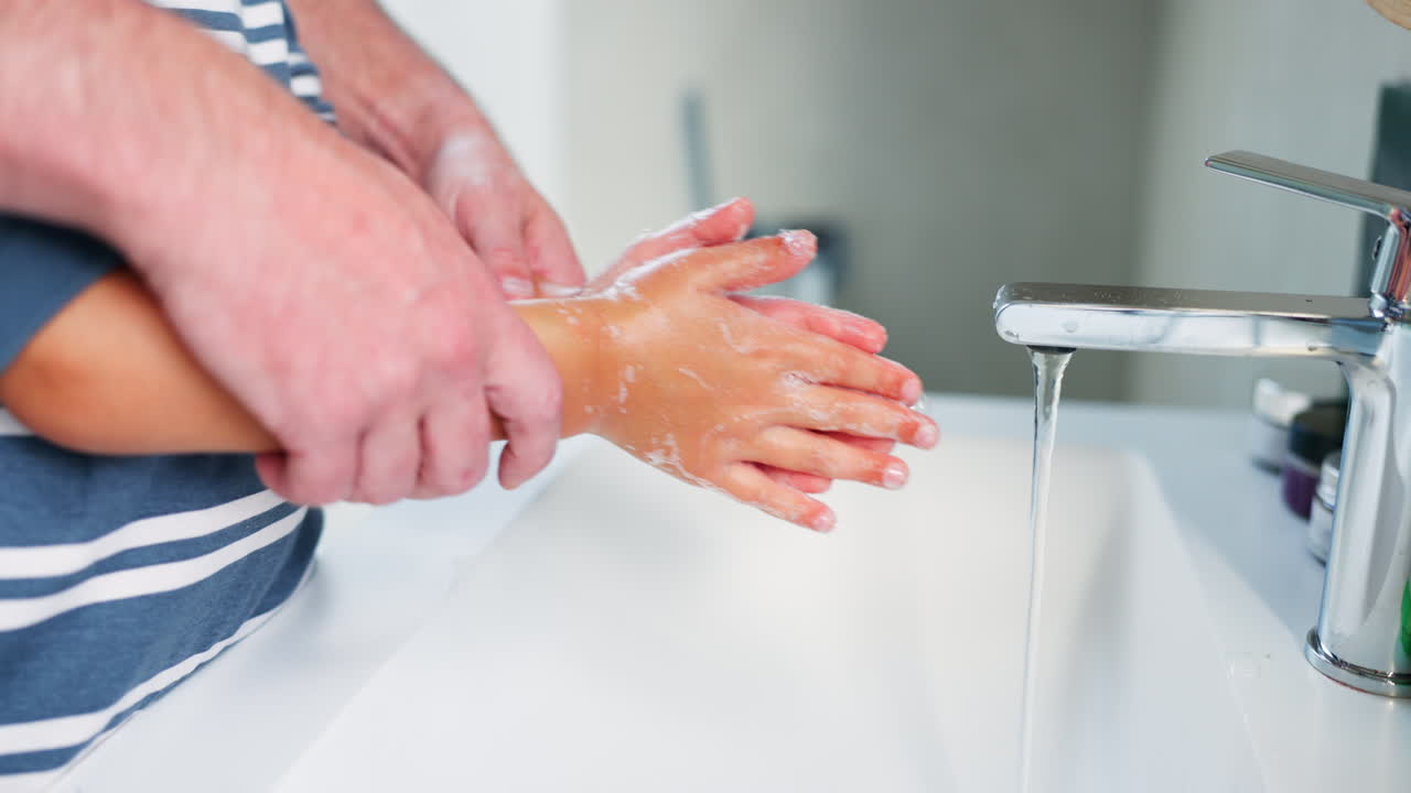 Foreldre, barn og vasker hender på badet