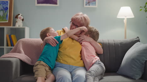 happy children kiss and embrace grandmother in living room