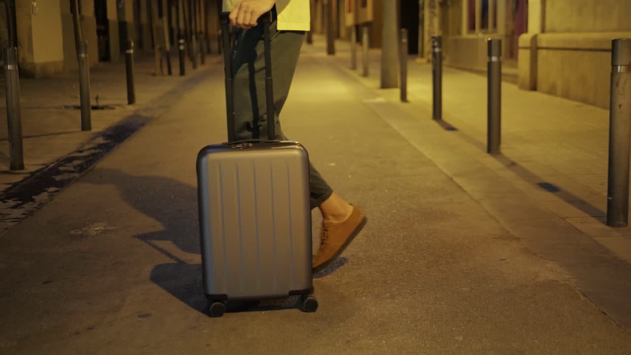Man walking with suitcase on a city street at night