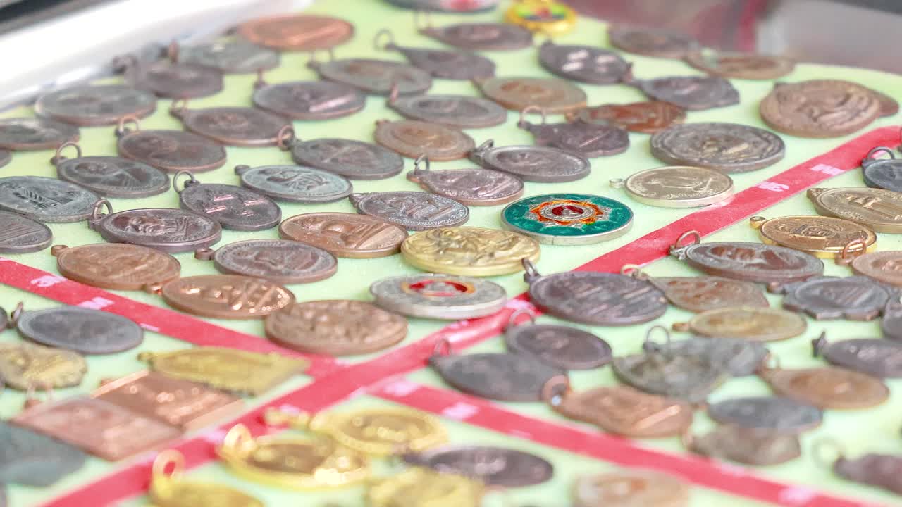 Close-up of amulets and Buddha statues on display in a vibrant street market in Phuket, Thailand. Bright lighting enhances details