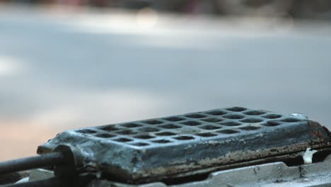 Close-Shot-of-a-a-Food-Vendor-Spooning-Batter-into-a-Waffle-Iron-by-the-Side-of-the-Road