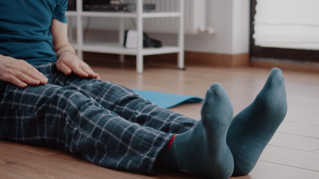 Close up of aged man doing stretch exercise on yoga mat