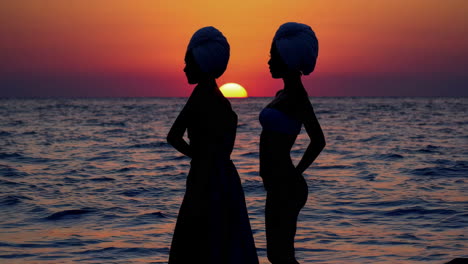silhouettes of two women at sunset on the beach