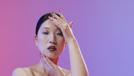 mujer asiática con cabello negro y maquillaje mirando a la cámara, copia espacio, cámara lenta