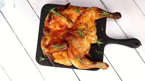 pollo asado entero con especias, salsa y piel crujiente en la tabla de cortar que gira en la mesa giratoria.