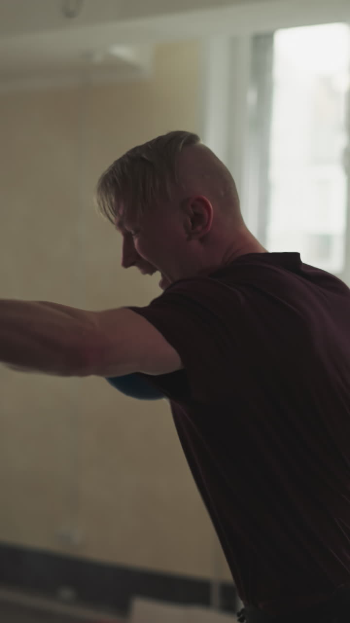 스포츠 클럽에서 싱백을 때리는 스포츠 선수, 권투 장갑을 입은 숙련된 운동선수, 체육관에서 무거운 물건을 공격하는 느린 동작, 무술 강사