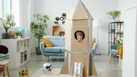 child playing in a cardboard rocket