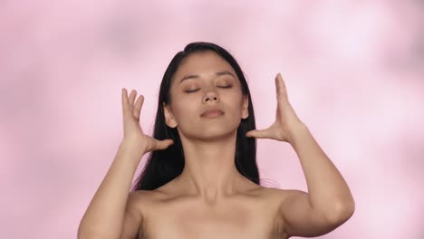 woman with closed eyes and hair pulled back against pink background