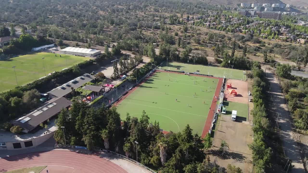 High definition aerial views of a hockey field during a match, zooming out gradually to show the surrounding landscape