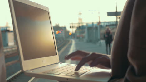mujer usando una computadora portátil en la plataforma de la estación