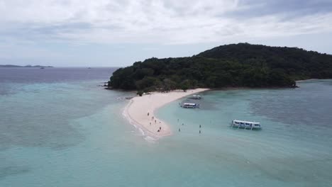 Gente-En-El-Banco-De-Arena-De-La-Isla-Ditaytayan-En-Coron,-Filipinas,-Con-Barcos-De-Isla-En-Isla-En-Aguas-Azules-Y-Claras.