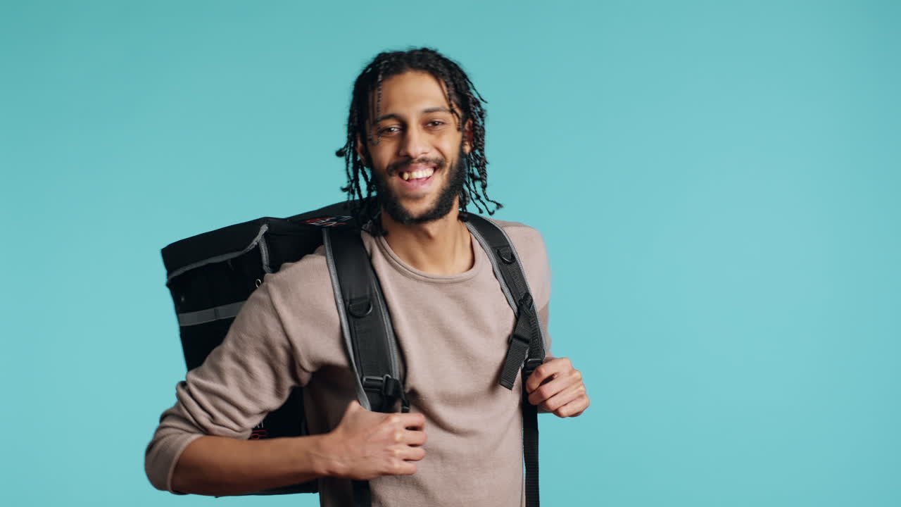 Happy delivery part time employee using thermal backpack to bring food order