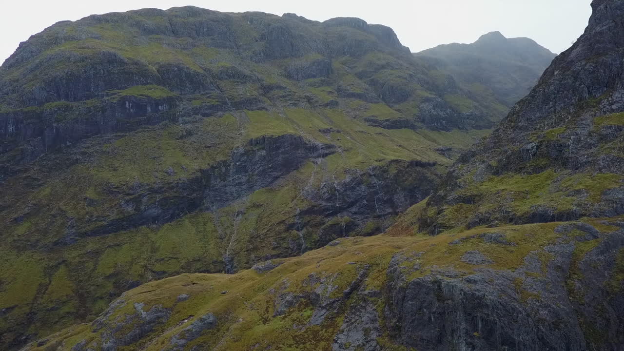 작은 폭포는 스코틀랜드 계곡의 험준한 산 절벽 경사면을 배수합니다.