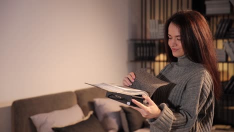 concentrated longhaired brunette looking through a catalog of furniture fabrics concentrated longhaired brunette looking through a catalog of furniture fabrics in a furniture showroom a selection of comfortable furniture for the bedroom and living room a careful selection