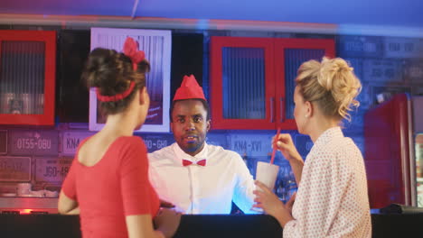 two pin up women talking to a waiter in a retro restaurant