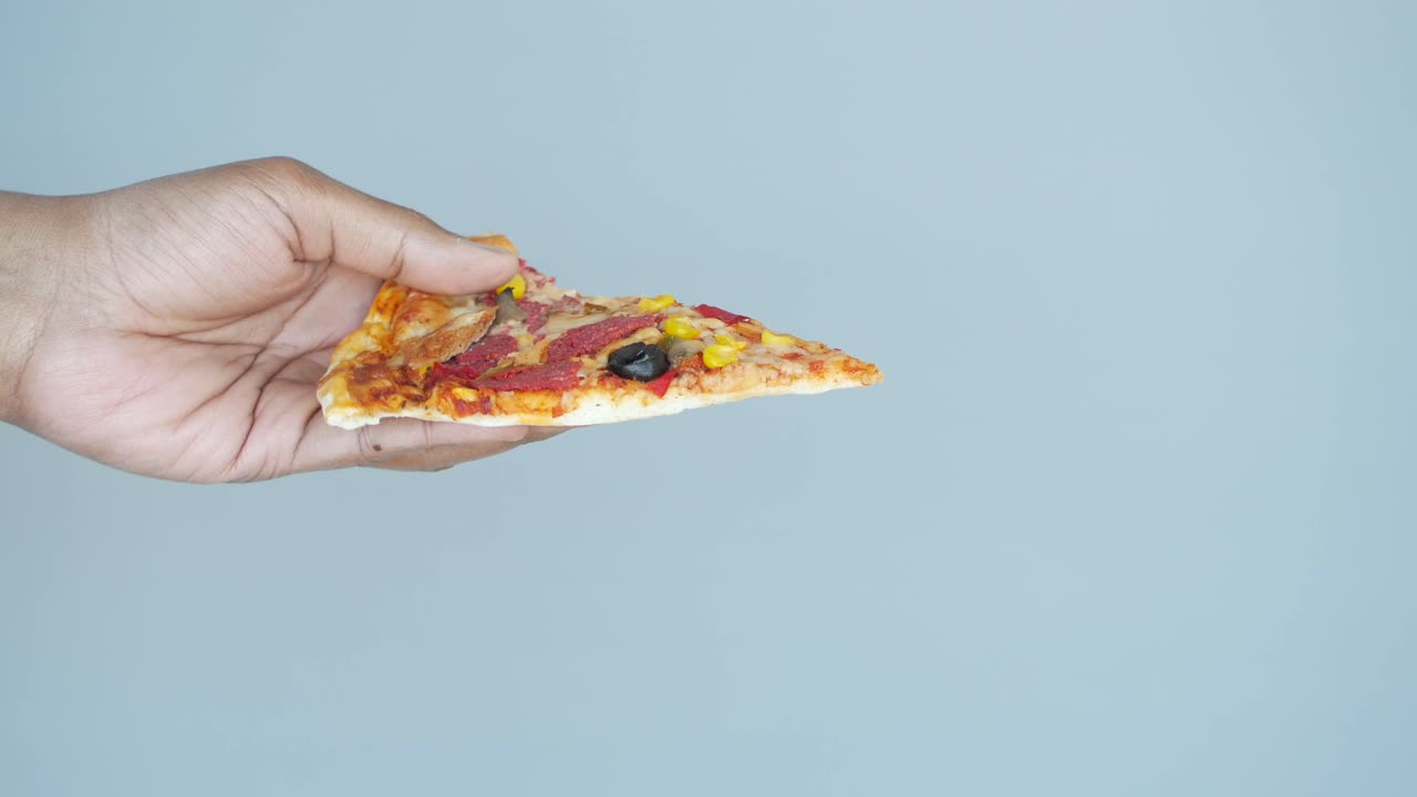 Hand holding a slice of pizza