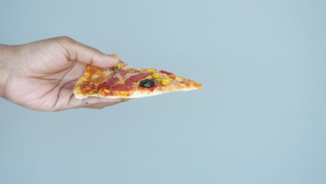 hand holding a slice of pizza