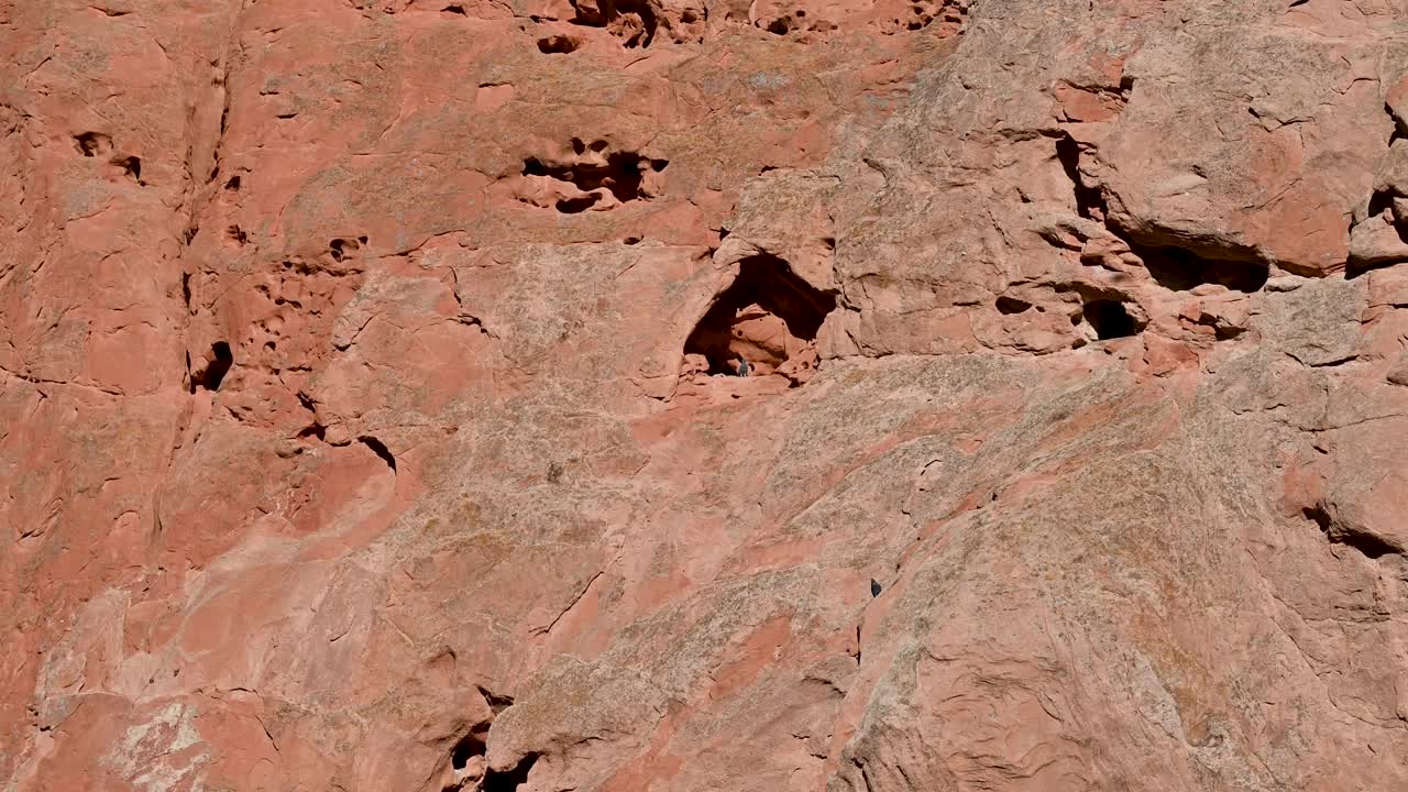 Aerial drone shot of towering red sandstone formations under clear blue sky in Garden of the Gods, Colorado