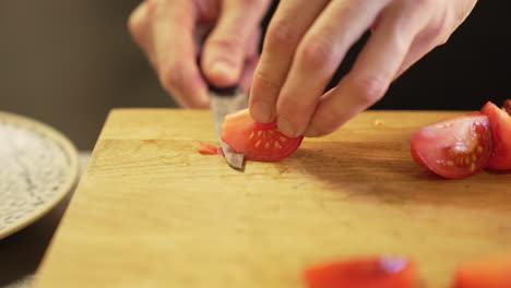 chef carefully peels a tomato with a knife on a wooden board using clean hands, demonstrating precision and hygiene