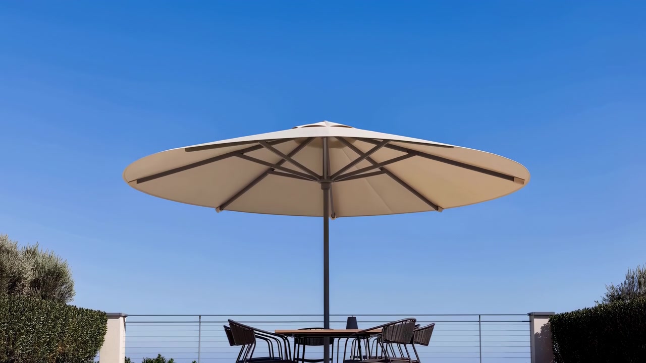 Una luminosa terrazza esterna presenta un ombrellone da patio chiuso sopra un tavolo da pranzo rotondo con diverse sedie, circondata da siepi potate e una ringhiera metallica.