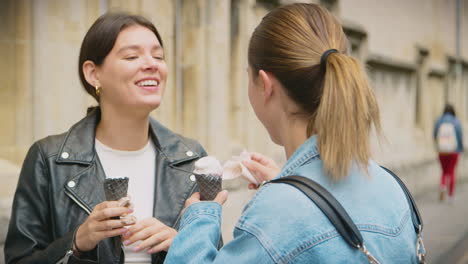 same sex female couple sightseeing and eating ice creams as they walk around oxford uk together