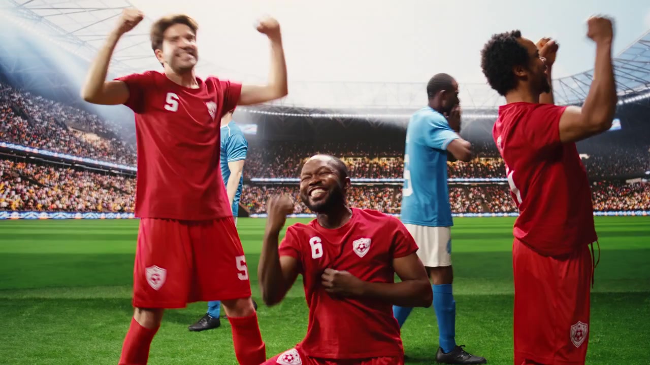 Rød fotballspiller kneler med knyttede never etter å ha scoret mål