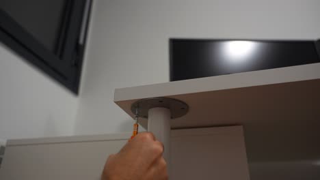 hombre casado desenroscando la pierna de la mesa con un destornillador pequeño para mover, vista estática