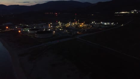 Aerial-approaching-factory,-oil-refinery-at-night