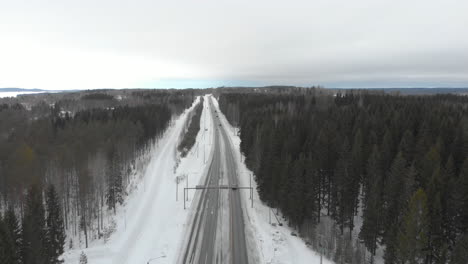 Antenne,-Rückwärts,-Drohnenaufnahme,-Des-Verkehrs,-Auf-Der-Straße-6,-Umgeben-Von-Schneelosen-Bäumen,-An-Einem-Bewölkten-Wintertag,-In-Kontionlahti,-Nordkarelien,-Finnland