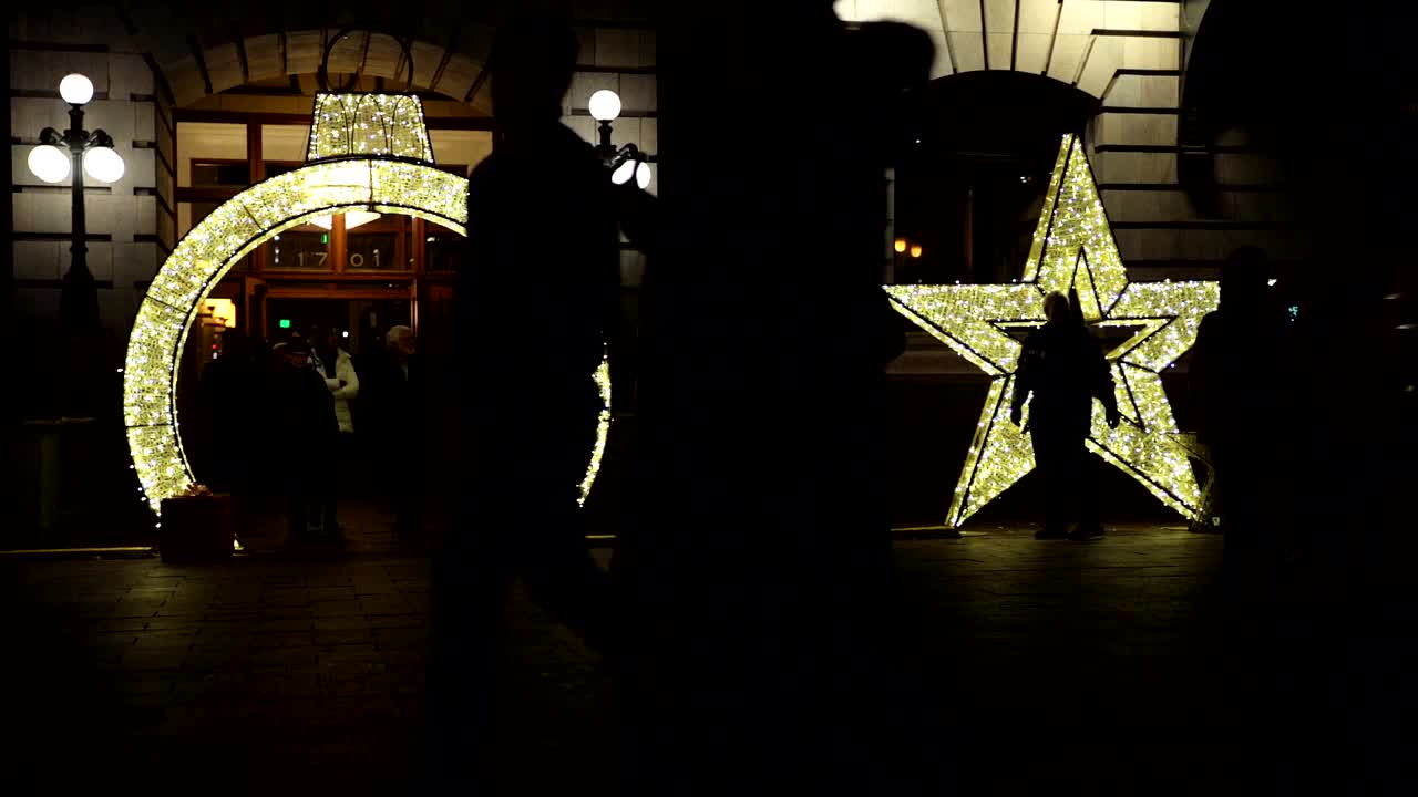 gente caminando frente a la decoración de luces navideñas en cámara lenta