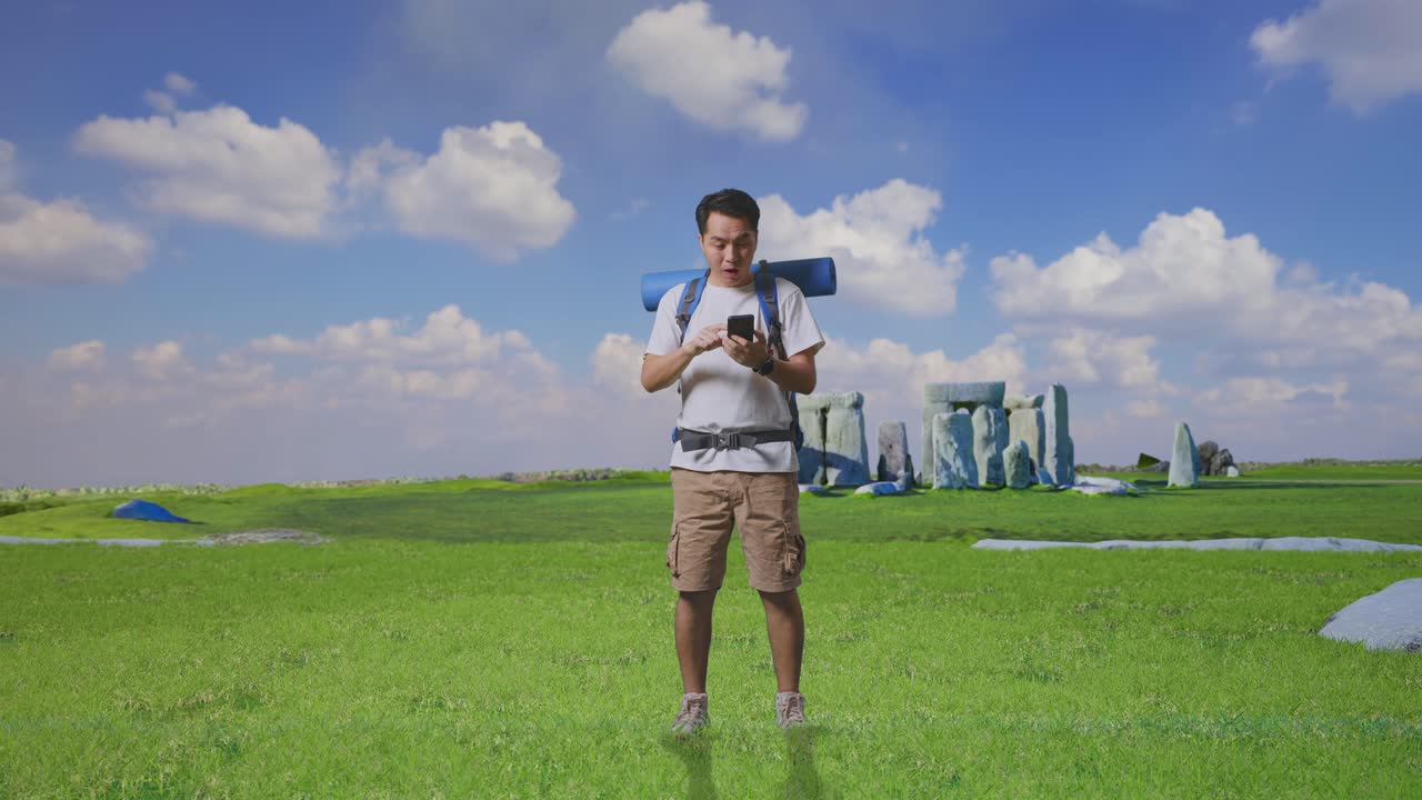 Full Body Of Asian Male Hiker With Mountaineering Backpack Looking At The Smartphone And Saying Wow While Traveling In Stonehenge
