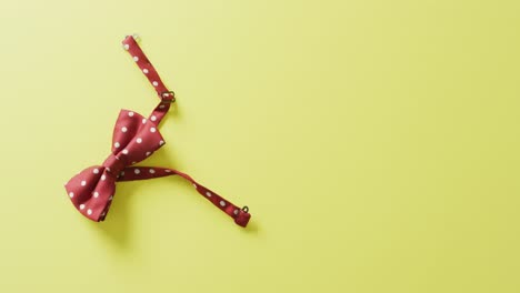 video of red dotted bow tie lying on yellow background