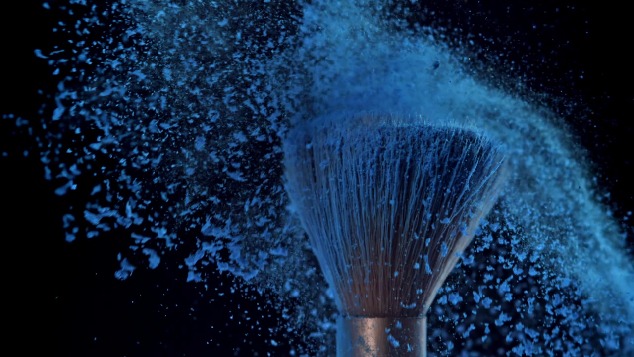 Polvere cosmetica blu che esplode su pennelli da trucco al rallentatore