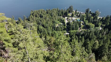 Young-male-hiker-sitting-atop-the-peak-of-Soames-Hill-overlooking-the-stunning-ocean-and-coastline-of-Gibsons,-Canada