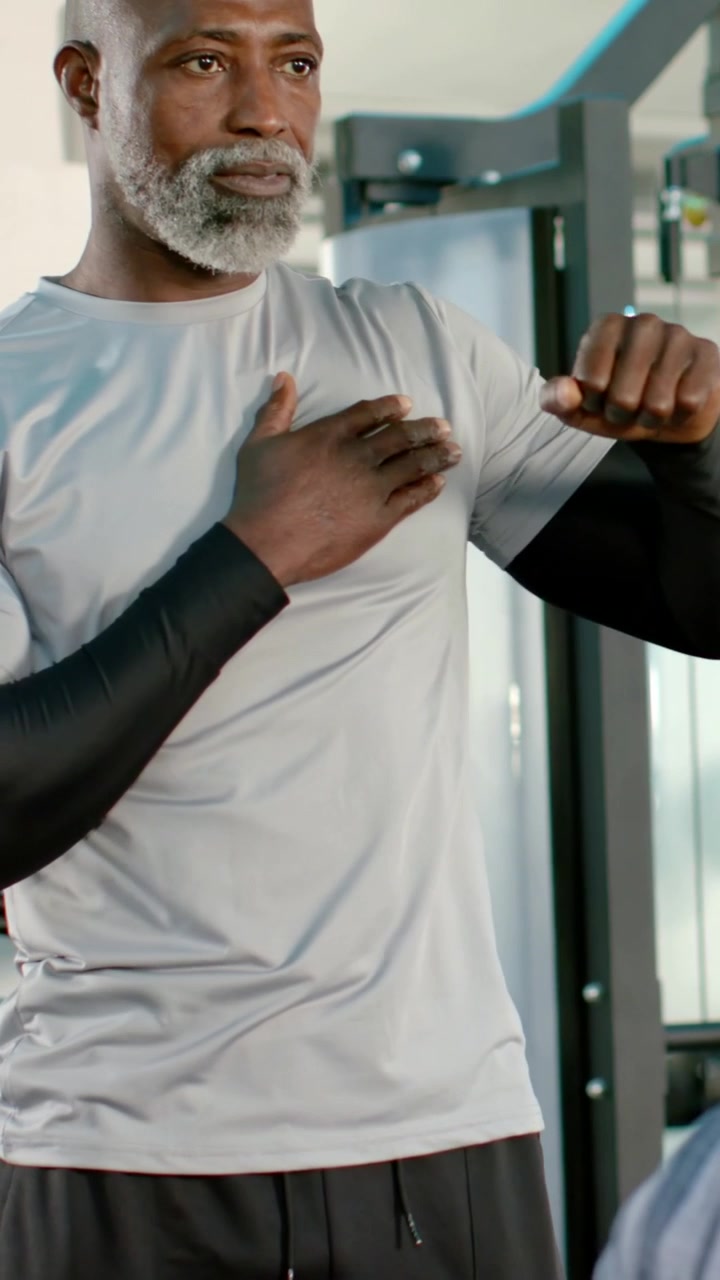 Vertical video: Placing hand on chest trainer in sleeves showing jab on cable at gym teaching