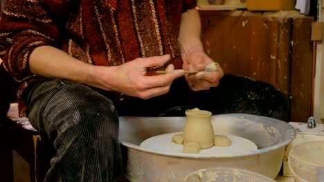 professional potter shaping mug with special tool in pottery workshop