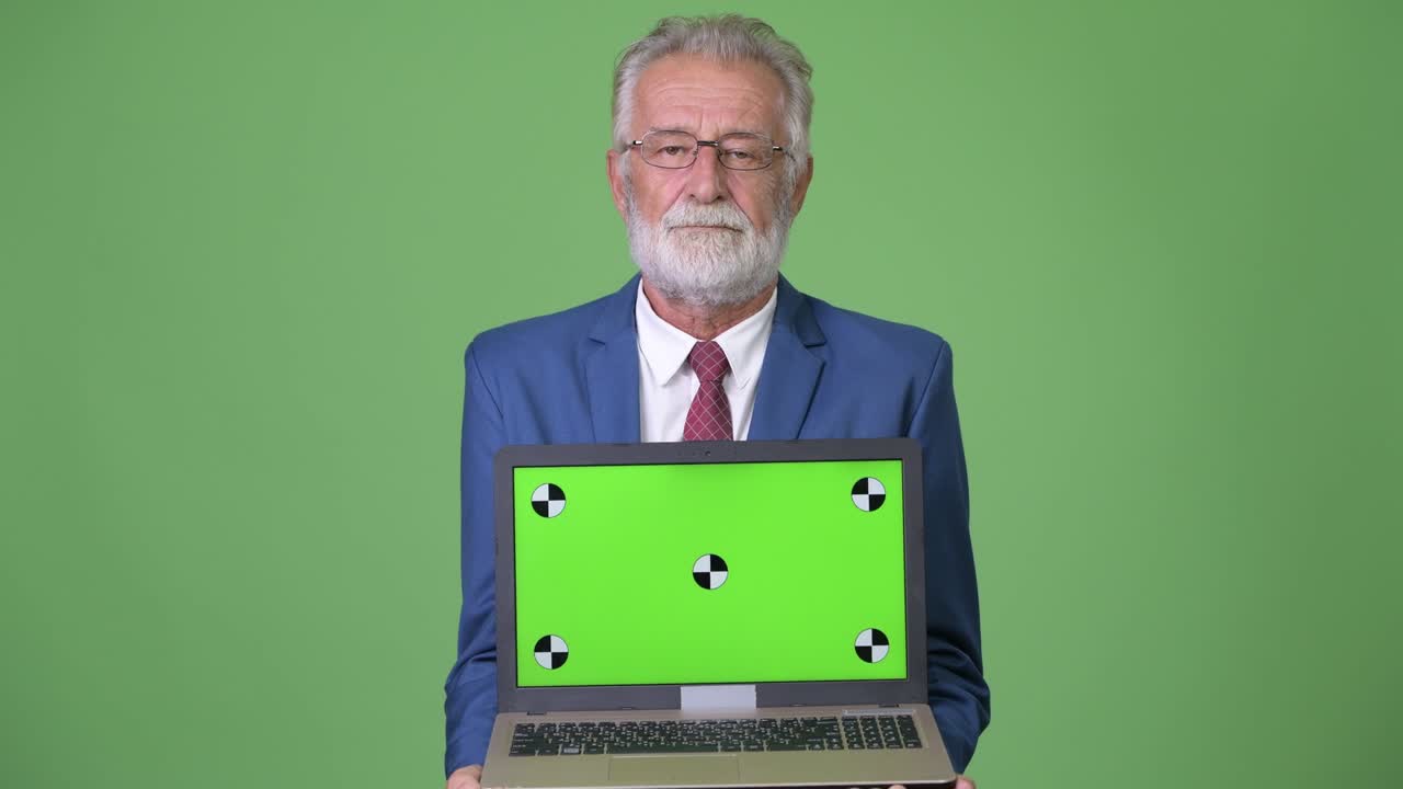 Empresário sênior barbudo e bonito contra fundo verde.