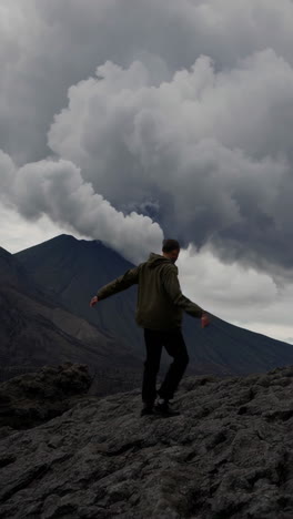 a man exploring a rugged volcanic landscape under cloudy skies