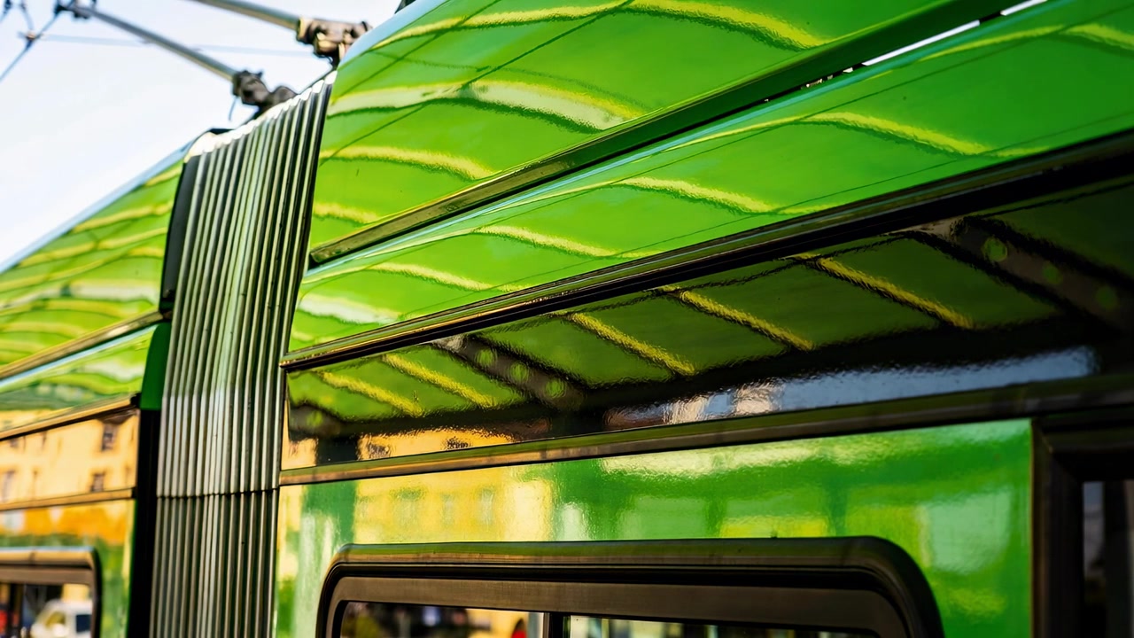 Toont zijkant groene tram trillend door lichte schok op station, reflecterend raam, balg, bovenleiding